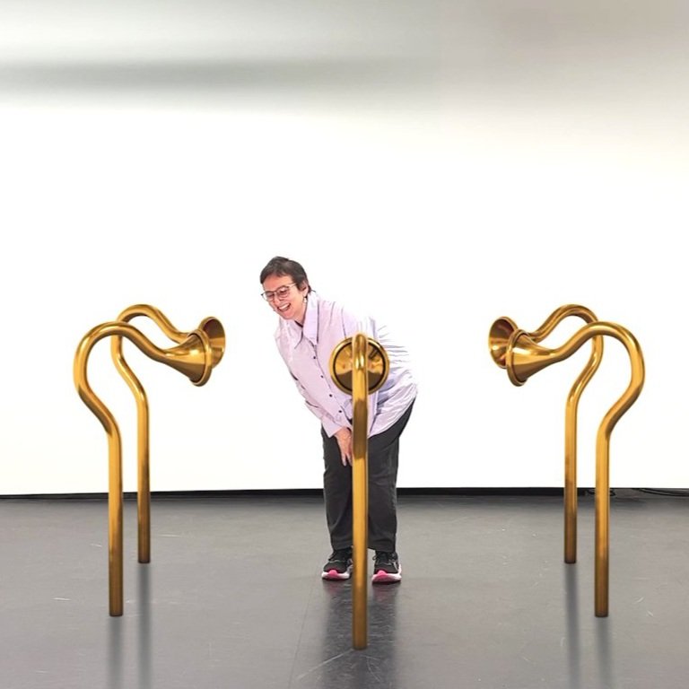 Parallel Lives: a person between two golden ear-trumpet sculptures