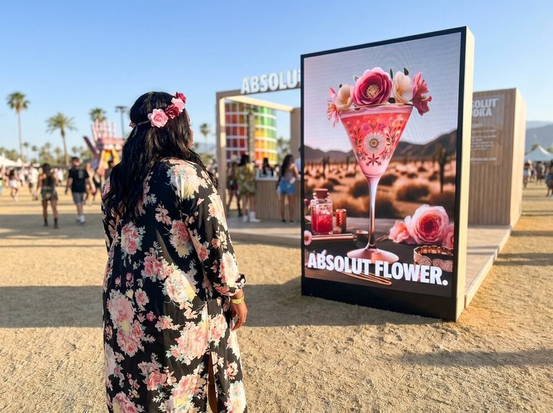 Participant in a floral dress beside her Absolut Flower cocktail screen