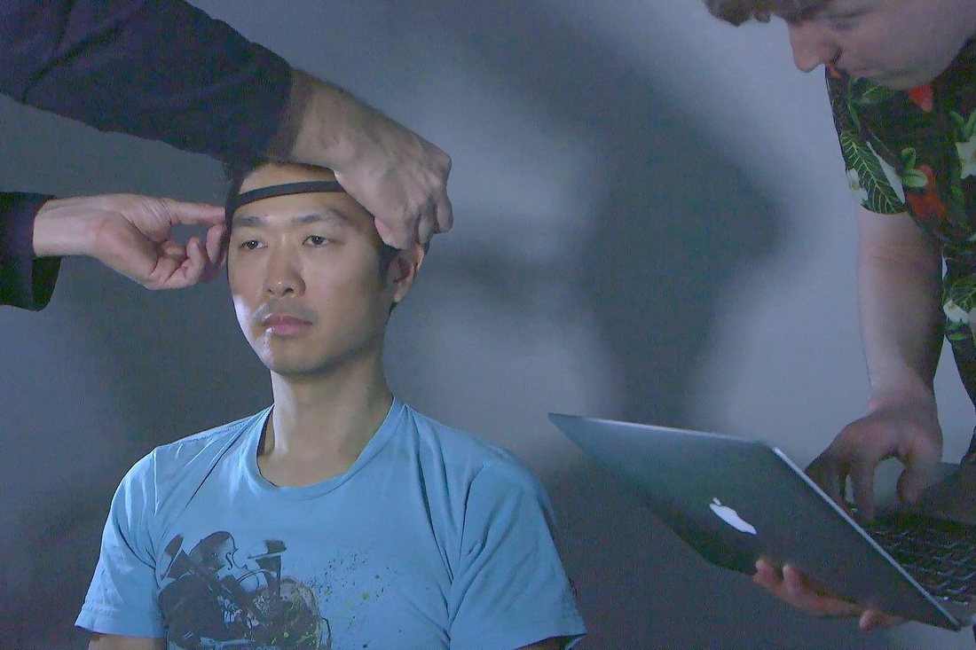 Fitting an EEG headset on a participant while his brainwaves are recorded