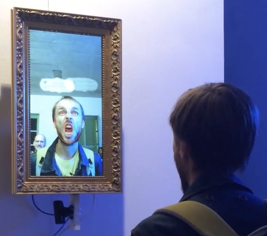 Emotional Mirror: man pulling a face at an interactive mirror in a gilded frame